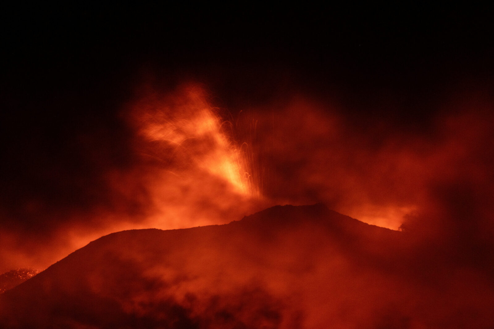 Mount Etna spurts red-hot lava into the night sky, as seen from Rocca Della Valle