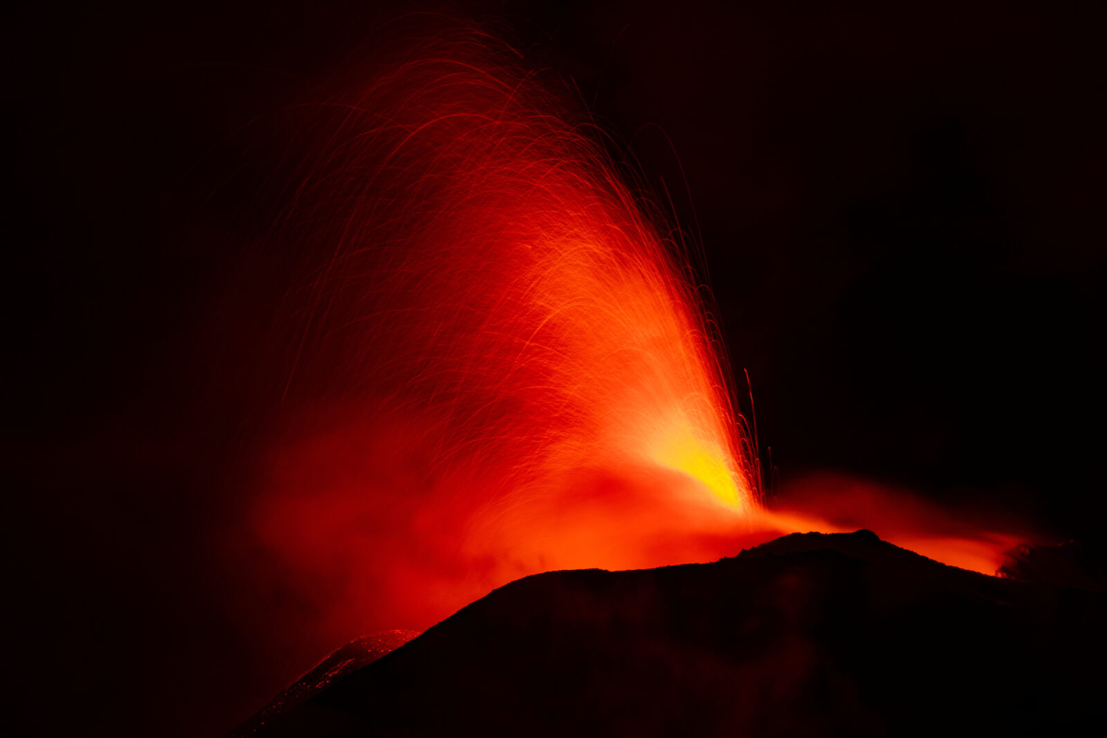 Mount Etna spurts red-hot lava into the night sky, as seen from Rocca Della Valle