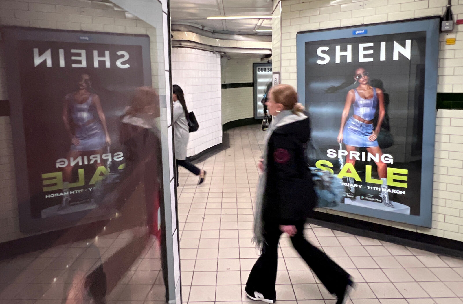 FILE PHOTO: People walk past an advertisement for Shein